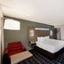 Quality Inn & Suites Irving Dfw Airport South guest room with king bed, red chair, and desk in Irving