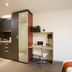 City Tempo Melbourne hotel room with kitchenette, desk and chair, mirrored wardrobe, and wall-mounted TV