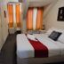 The Shakespeare Hotel Auckland guest room with double bed, orange curtains, and compact seating area