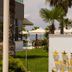 Santa Beach Hotel in Agía Triáda with palm trees, pool umbrellas, and a sea view