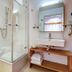 Alpenparks Hotel Maria Alm bathroom with glass shower, wall-mounted sink, and toilet in Maria Alm am Steinernen Meer
