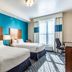 Fairfield Inn & Suites by Marriott Alamogordo room with two beds, teal accent wall, and desk by window