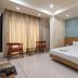 Hotel G Shy, Bhopal guest room with double bed, curtains, and two stools beside a small table