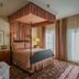 Mendocino Hotel and Garden Suites bedroom with canopy bed, floral carpet and balcony doors in Mendocino