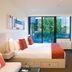 City Tempo Melbourne room with bed, desk, wall TV and balcony view of a pool and trees