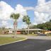 Prince of Wales Motel in Lake Wales exterior with palm trees and a paved driveway under a cloudy sky