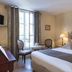 Aux Vieux Remparts in Provins: elegant guest room with ornate twin headboards, window seating and lamp