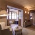 Hotel Ciasa Salares room in Badia/Abtei with bed, seating area and bathroom doorway