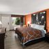 Super 8 by Wyndham Bulls Gap Greeneville Area guest room with king bed, orange accent wall, and window view