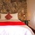 Rumi Wasi in Cusco room with stone wall, double bed, red runner, and bedside lanterns