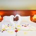 Esmeralda Hotel in Kremastí: heart-shaped towel swans and rose petals on a neatly made bed