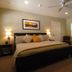 Queen's Inn By The River Oakhurst guest room with king bed, bedside lamps, ceiling fan, and chair