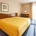 Apart-Hotel Halle, Halle: twin beds in a bright guest room with bedside lamps and a window view