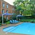 Town Lodge Menlo Park in Pretoria with outdoor swimming pool, blue loungers and umbrellas beside a brick building.