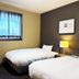 Hotel Route-Inn Court Kashiwazaki room with two single beds, window and bedside lamp in Kashiwazaki