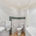 Aristotles North Shore in Auckland bathroom with bathtub, toilet, sink and tiled walls