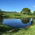 Llwyn Onn Guest House in Betws-y-Coed beside a tranquil pond with grassy banks and blue sky