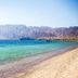 Time Coral Nuweiba Resort beach with clear turquoise sea, mountains, and a pier in Nuweiba