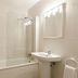 Bathroom at Tahití Playa Suites in Santa Susanna with bathtub, sink and lit mirror