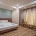 Hotel G Shy Bhopal guest room with double bed, wooden floor, and seating by curtains