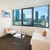 City Tempo Melbourne apartment with city skyline view, white sofa and glass coffee table