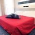 Hotel Michelangelo in Biella guest room with red bedspread, striped pillow and large sheer-curtained window