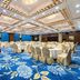 The Greenway Hotel Xiamen banquet hall with round tables, gold chairs and a small stage