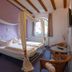 Hotel Schlosshof in Dolgesheim, four-poster bed room with arched window and wicker chairs