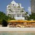 Palm Heights in North Side with beachfront seating and white villa-style hotel facade