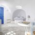 Aghios Artemios Traditional Houses in Thera: white cave-style room with bed, seating area, and blue door