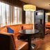 Courtyard by Marriott Fayetteville lounge with orange booths, round tables, and wood flooring