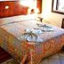 Maratea Mare Florianopolis guest room with double bed, patterned bedspread, bedside lamps and tiled floor