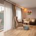 Hotel am Schlosspark Husum living area with sofa, armchair, TV, and balcony door to garden view