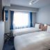 Toyoko Inn Koriyama guest room with two single beds and window with blue curtains in Kōriyama