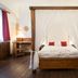Hotel U Malého Vitka in Český Krumlov, four-poster bed with white curtains in a simple guest room