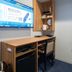 Toyoko Inn Koriyama guest room workspace with wall-mounted TV, desk, chair, and window curtains