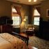 The Borland House Inn in Montgomery bedroom with four-poster bed, windows, armchair, and floor lamp