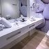 Bathroom at Tahití Playa Suites in Santa Susanna with double sink, toilet, and pebble wall mural