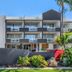 The Wellington Apartment Hotel in Brisbane exterior with balconies, landscaped entrance, and blue sky