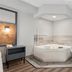 AmericInn by Wyndham Wisconsin Dells corner whirlpool suite with plaid chair and ottoman