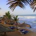 The Kairaba Beach Hotel in Serrekunda with beachfront loungers, palm trees, and ocean waves
