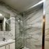 Villa Montmartre in Paris bathroom with glass shower, marble-look tile walls and white vanity