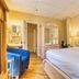 The Stratford Hotel by Hoco Hotels Collection guest room with bed, blue chair, wardrobe and vanity