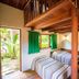 Pouso Sambaquis in Ilhabela with wooden loft beds, green curtains, and garden-view windows