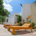 Hotel Maria de Lourdes, Cancún: outdoor patio with wooden lounge chairs and white stucco walls