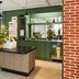 Campanile Nature - Sannois Ermont lobby with green front desk, pendant lights, and indoor plants in Sannois