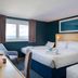 Travelodge Newbury Tot Hill room with three beds, window view and teal accent walls in Newbury