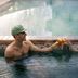 Gravity Haus Steamboat indoor pool with two guests toasting drinks in the water