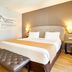 Eurostars Patios de Cordoba bedroom with double bed, tufted bench, and wall sconces in Córdoba.