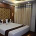 Hotel Apple Valley, Kodaikanal guest room with king bed, wood-paneled wall and curtain-dressed window